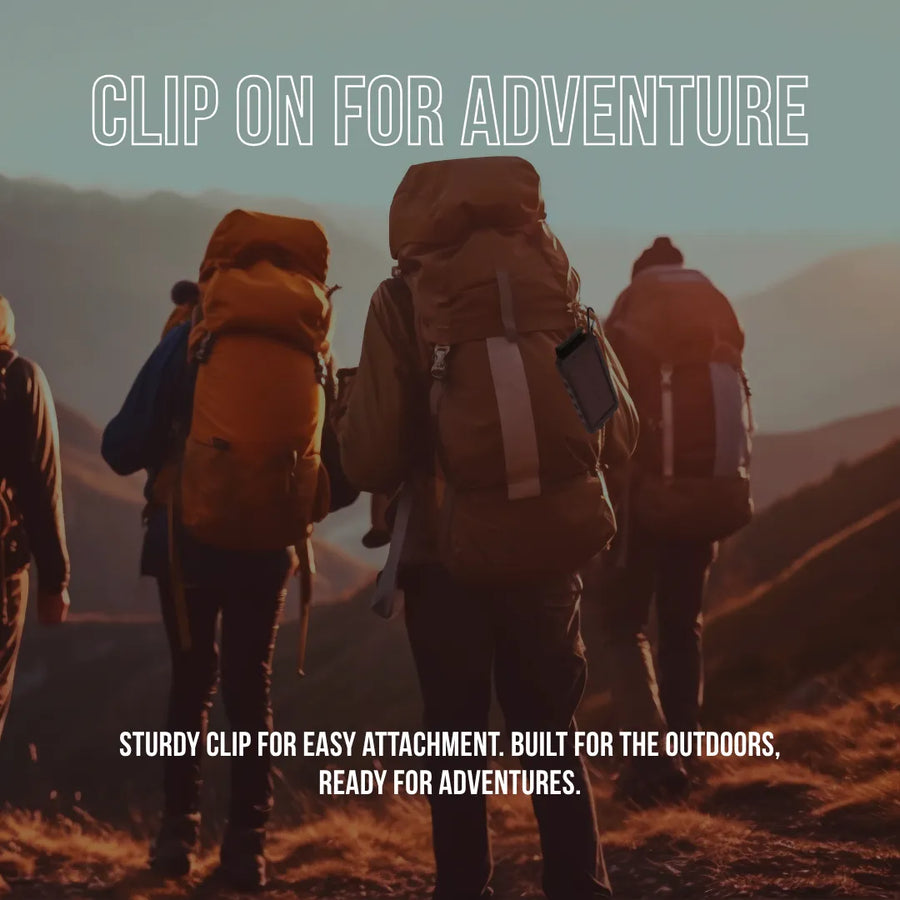 Hikers with backpacks using a clip-on power bank outdoors at sunset, ready for adventure.